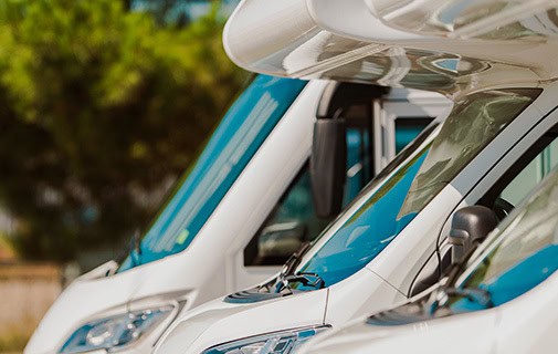 Weiße Reisemobile in Reihe mit Windschutzscheiben